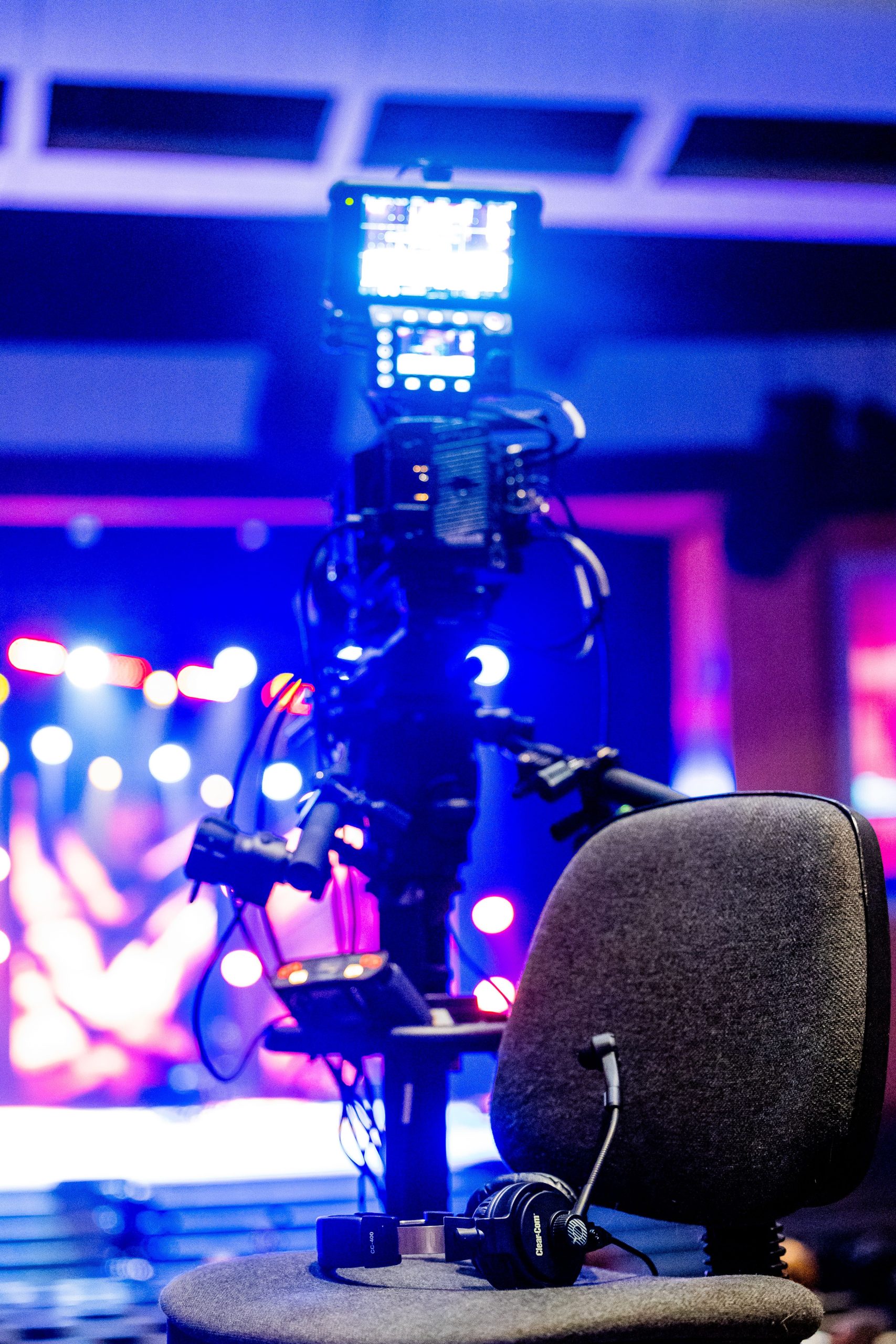 Close-up of a professional camera setup with a chair and headset in an auditorium.